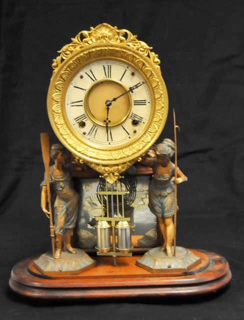 The Crystal Palace clock: Patented Jan. 26, 1875. Metal sculptures "Boy with Oar & Gil with Harpoon" on wooden stand. Clock has gilt bezel. Approx. 16.5" x 14" Please read our terms of sale.