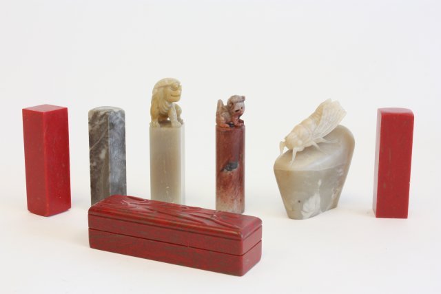 3 chicken blood stamps & 4 pieces soapstone: 1 stamp in carved floral chicken blood stone box with artist signature, approx. 4" x 1" x 1". Carved soapstone including carved "Bug on Book", wings broken, approx. 3". 3 soapstone stamps, 2 of Foo Do
