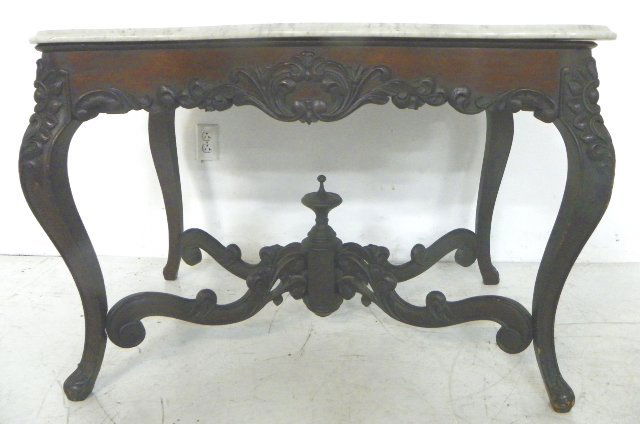 Rococo marble top rosewood center table: Serpentine, rectangular marble top with applied carvings on the apron, long cabriole legs with carvings at the knees & foot, thin pierce carved serpentine stretchers with octagonal center post & turne