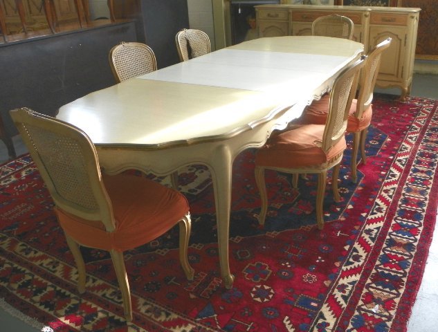 Off white Louis XVI style table with 6 chairs: Chairs have cane back, table has 2 leaves & matching buffet, chairs need recovering. 8 pieces in total. Table approx. 40" x 64", buffet 72" across. From the Riverdale, NY estate of Nell Martinis.