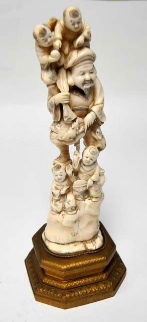 Bone figure on gilt metal pedestal: Depicting: "4 Children Playing with Old Man". Approx. 14" H. Please read our terms of sale.