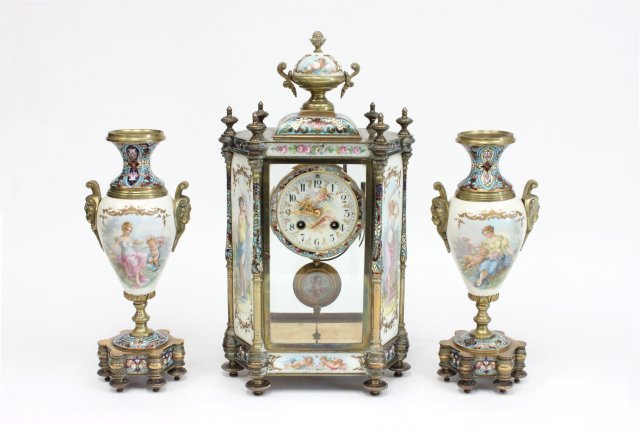 19th c. French enameled crystal & bronze clock set: 19th c French bronze crystal and enamel clock set. Depicting female and putti, porcelain face & porcelain pendulum. Clock is 17" x 8 1/2", urns are 12" H by 5 1/2".