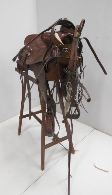 17" highly tooled Western saddle & accessories: With 1952 silver dollar inlaid in horn with cinch. Including matching chest plate & full head stall bridle, reins, & snaffle bit. From the Colts Neck, NJ estate of Duncan Thecker.