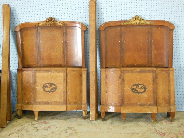 Pair brass mounted figural French walnut beds: With "Cherubs", with mother of pearl & satin inlays, ca. 1920's-30's, headboards 44 1/2"W x 63 1/4H, footboard 44 1/2"W x 34"H Rails are warped. Veneer damage to legs.