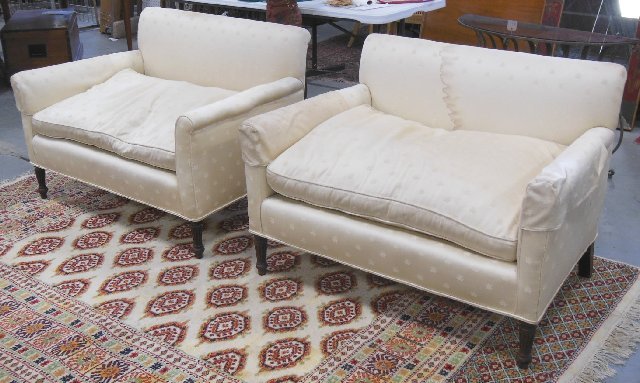 Pair Neo-Classic style love seats: From the Estate of Chris Peckham. Cream upholstery. Approx. 31" H x 44.5" W x 31" D. Upholstery stained & worn. Scratches on feet.