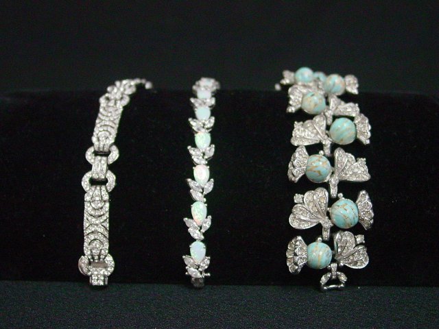 Costume bracelets with stones: Approx. 3 bracelets including 1 Ciner bracelet with clear rhinestones. 1 Sterling silver bracelet with opals. 1 foliate design bracelet with clear rhinestones and blue stones. From the estate of Anita