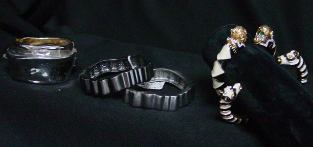 Designer costume bracelet lot: Approx. 5 bracelets including 2 Kenneth Lane black & white enamel animal bracelets, 2 Paige Novick silver tone bangles and a Ciner silver tone hinged bracelet. From the estate of Anita Stern, owner of