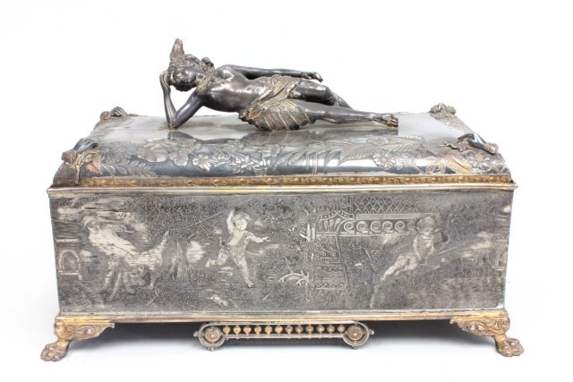 Victorian Silver Plated Figural Box: Decorated with semi nude reclining woman on top and children at play all around the sides. Approx. 7" h, 12" w, 6" d. Some dents.