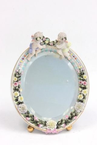 Dresden style oval table mirror with Putti: Floral decoration. Approx. 12.75" x 10.25".