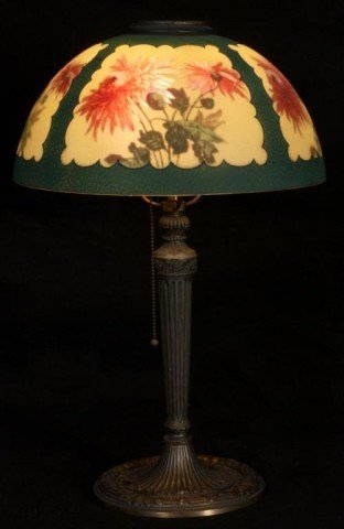 Pittsburgh Chrysanthemum table lamp: Hand painted glass. 4 framed panels of flowers & green background. Electrified. Metal base signed, E.M. Co. Approx. 22" H x 14" D (shade). Chip on edge. Good condition. From the estate of John Sciorti
