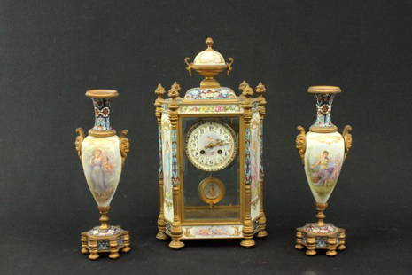 French Japy Freres Champleve clock garniture: With porcelain mounts, ormolu, decorated with dancing maidens. Late 19th century. Clock approx. 18" H. Urns approx. 13.75" H. Slight wear to patina on gilding.