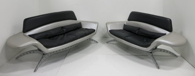 Matched pair Memphis style leather & metal sofas: Circa 1980. Upholstered in black & silver metallic leather, with adjustable headrest. Approx. 35.5" H x 79" W x 33" D. Smaller approx. 35.5" H x 92" W x 33" D. Minor wear to leather.