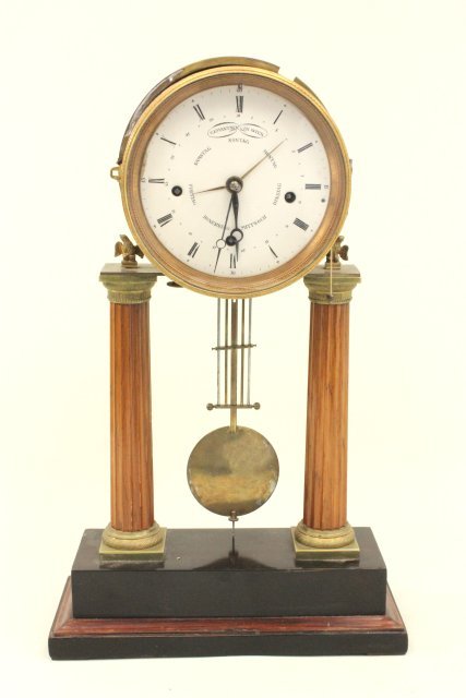 German 19th C Mantle Clock: Empire style clock with round face supported on 2 wood columns resting on black marble. Approx. 20" high.