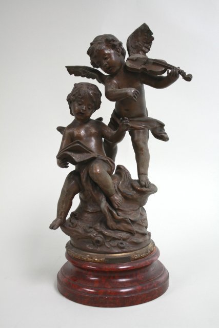 French Spelter Grouping: Depicting two winged cupids with violin & music notes. Signed Rousseau. Mounted on wood base. Plaque on base,"Duo D'amours par Rousseau". Approx. 16" H. Some losses. Crack in seated cupid's arm. Tips 