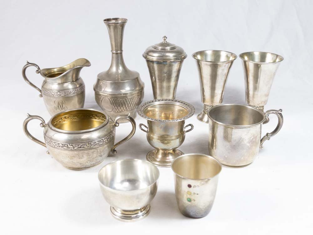 Lot of Sterling Silver Pieces: Including sugar and creamer, child's mug, bud vase, toothpick holder, shotglass, 3 .800 wine cups, and a covered piece. 10 pieces total. Approx. 21.77 ozt.