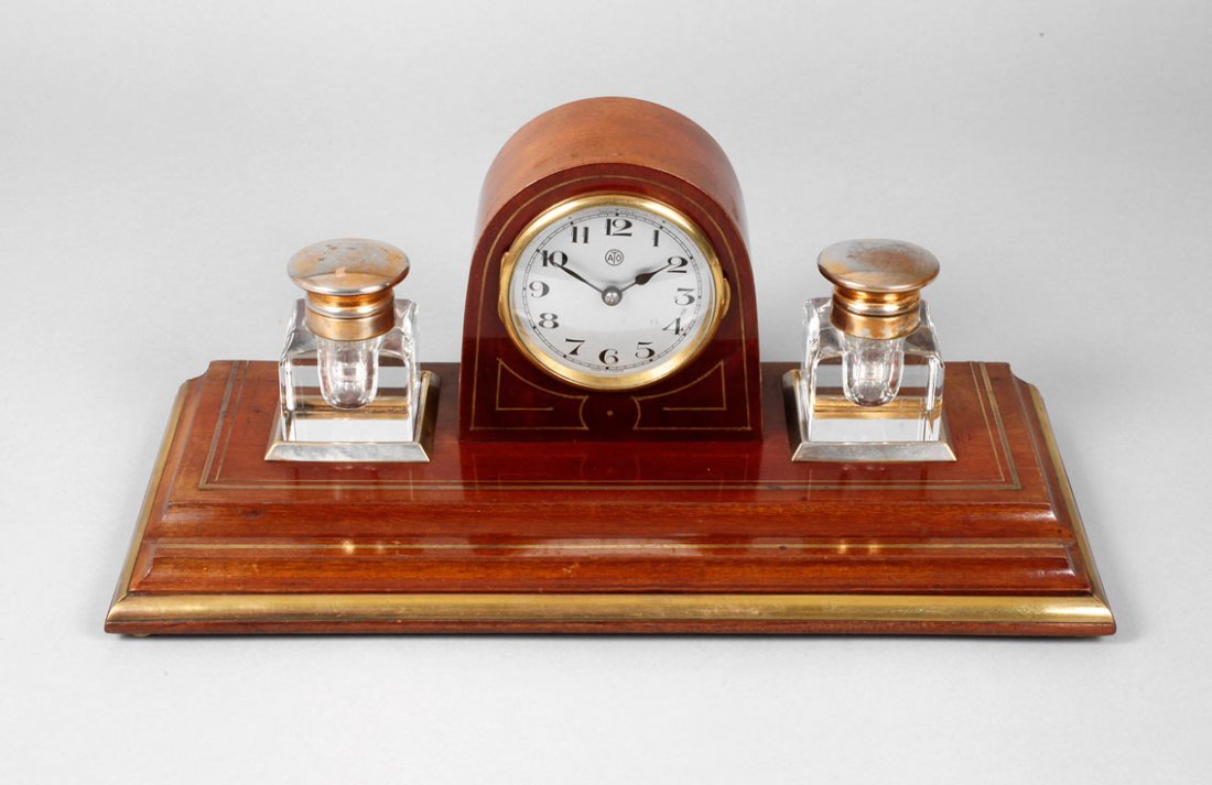 Schreibtischuhr ATO: gemarkt Leon Hatot Fabricants Paris/France, elektromagnetisches Uhrwerk, Mahagonigehäuse mit Messingeinlagen, seitlich zwei Tintenfässer aus Kristallglas mit versilberten Messingdeckeln, diese leich