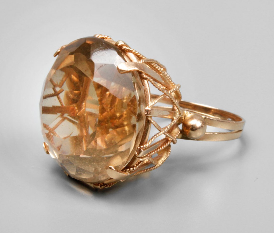 Ring mit Citrin: 2. Hälfte 20. Jh., Gelbgold 750 geprüft, Ringkopf mit facettiertem Citrin in Krappenfassung, Fassung mit kordiertem Golddraht verziert, Ringschiene teilweise geteilt, RW 16,5 mm, Gewicht ca. 11,9 g.