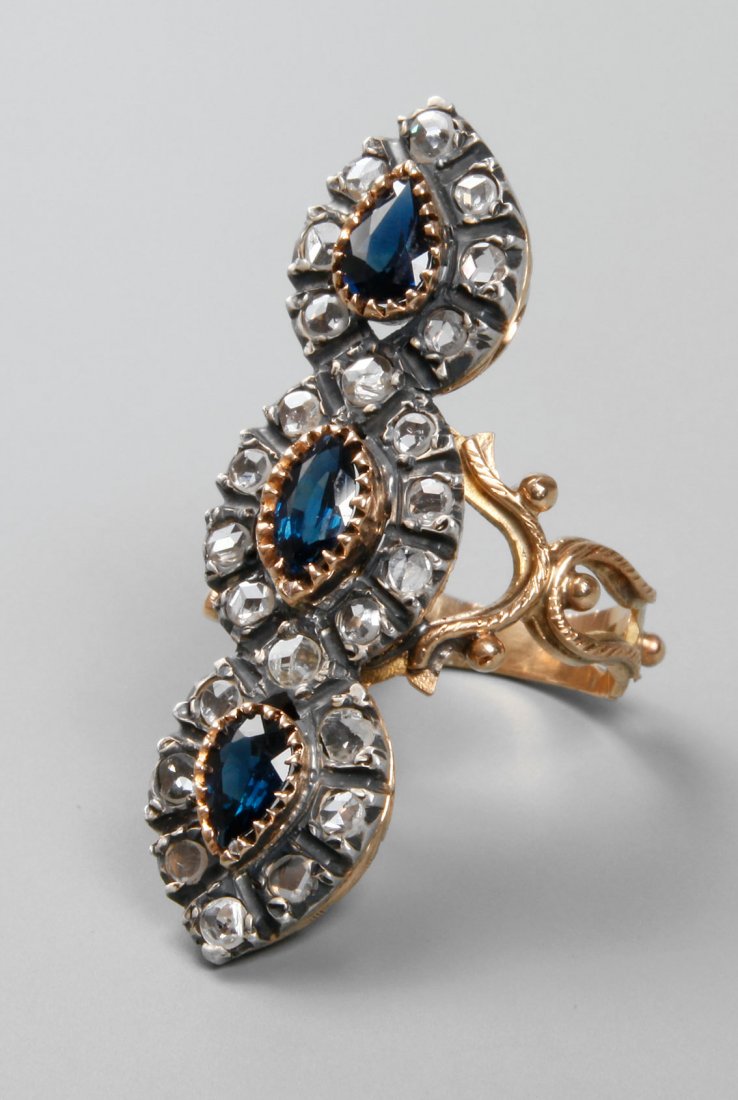 Großer Biedermeier-Diamantring: um 1850, 750 Gelbgold geprüft, besetzt mit drei tropfenförmigen Saphiren, der mittlere L ca. 7 mm, umgeben von 25 Diamanten, je ca. 0,05 ct, die Goldfassungen fein graviert, ornamental gestaltete Ri