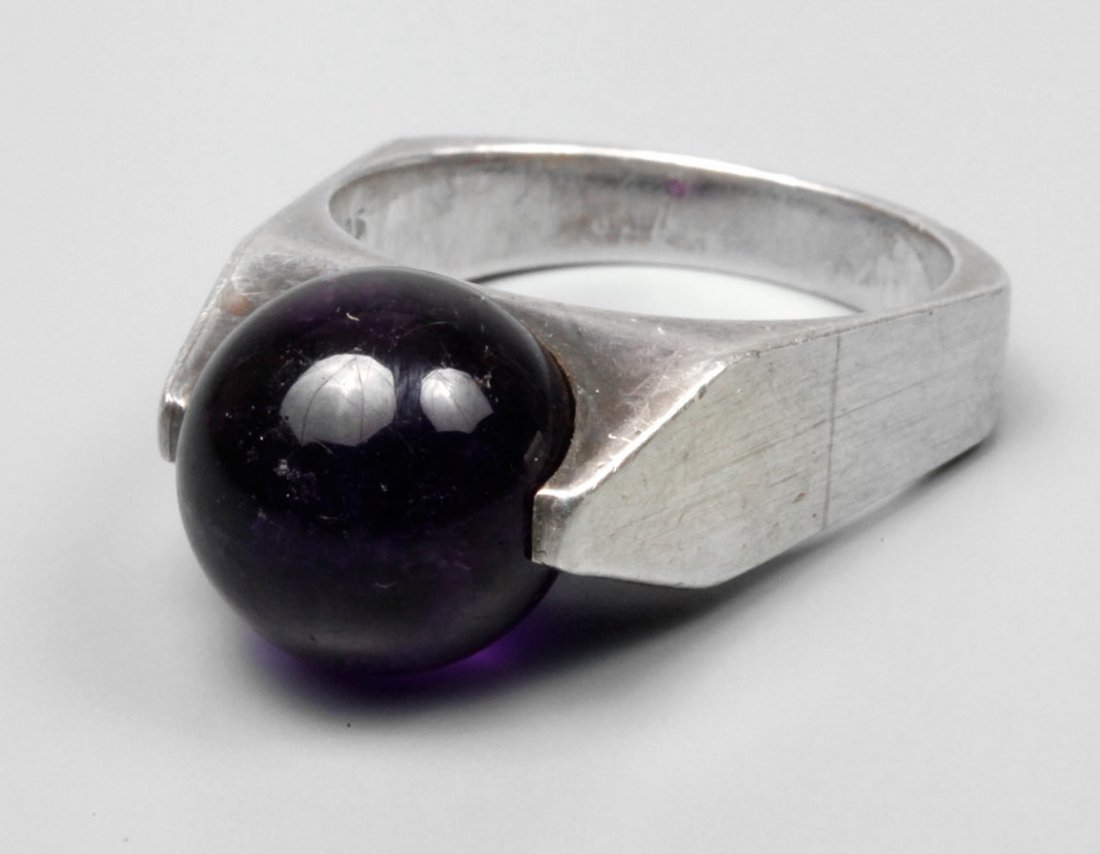 Silberring mit frei beweglicher Amethystkugel: um 1970, Silber gestempelt 925 und Herstellerpunze, Ringkopf besetzt mit frei drehbarer Amethystkugel in dunkelvioletter Farbe im Durchmesser von 11 mm, RW 17,5 mm, Gewicht 8,5 g.