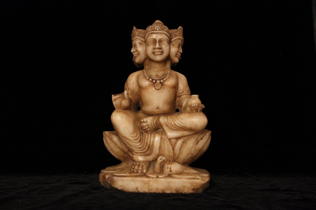 Four faced Brahma in white soft marble: Statue of four faced two armed Brahma sitting on a lotus flower. His vehicle bird (transcedental carrier) the swan Hamsa is at his feet. His left hand holds a vase, partially broken right hand makes t