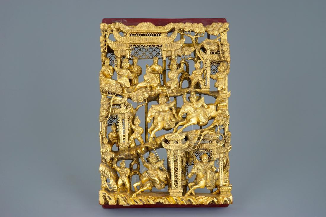 A Chinese carved gilt wood panel with a fighting scene, (1 of 2)