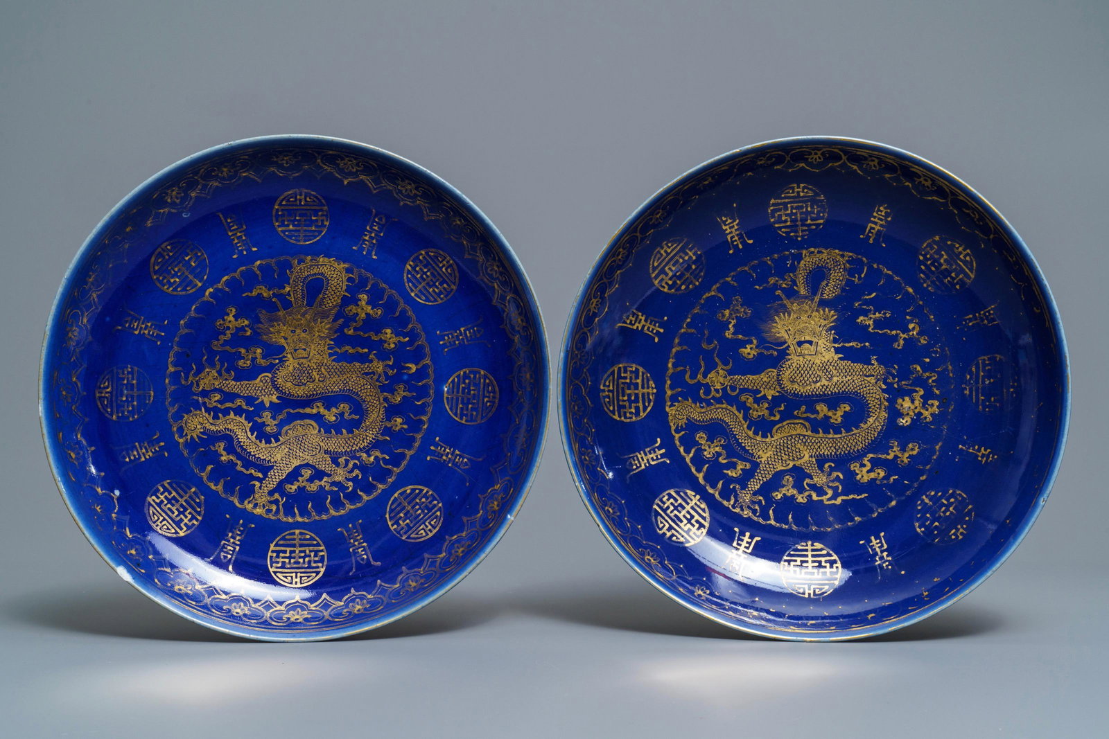 A pair of Chinese gilt-decorated blue-ground 'dragon': A pair of Chinese gilt-decorated blue-ground 'dragon' dishes, Guangxu mark and of the period -- Dia.: 34,5 cmÂ Condition: (UV-checked) - The first with a reglued break across, from ca. 4 to ca. 11 