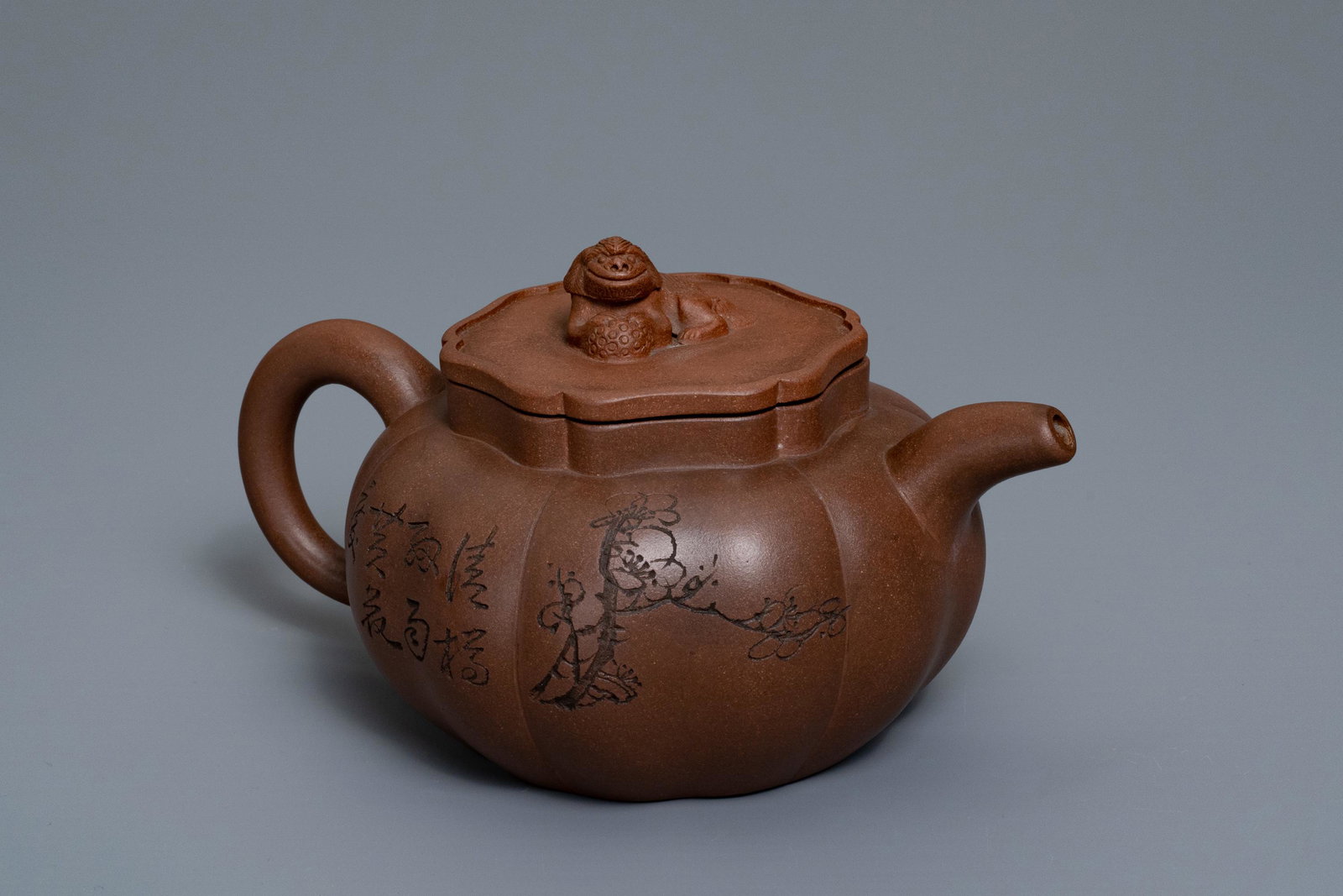 A Chinese Yixing stoneware teapot and cover with: A Chinese Yixing stoneware teapot and cover with inscription, impressed seal marks, 19/20th C. -- H.: 10,5 cm - L.: 19 cm