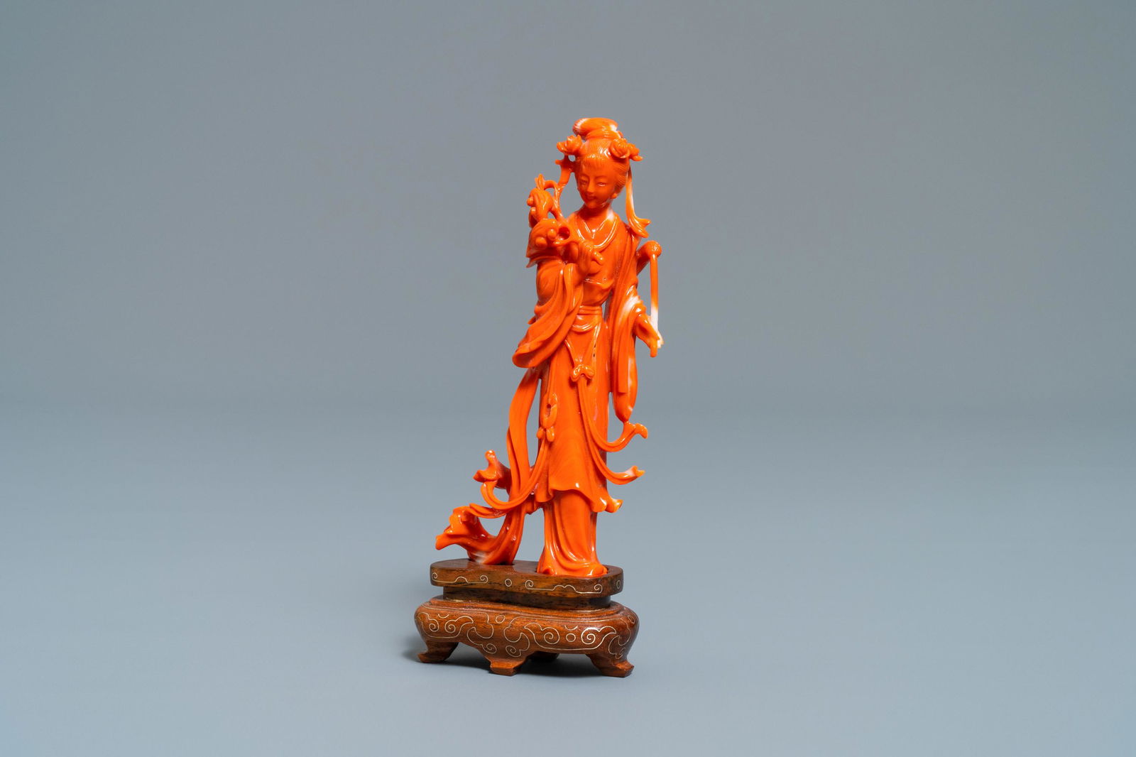 A Chinese carved coral figure of a lady with lingzhi,: A Chinese carved coral figure of a lady with lingzhi, 19/20th C. H.: 14 cm (incl. stand) H.: 11,5 cm (excl. stand)