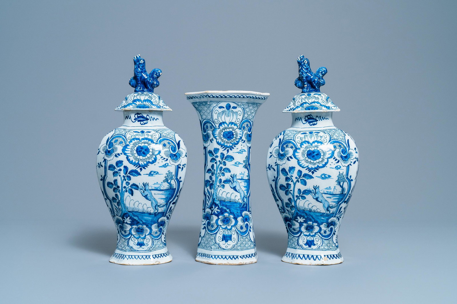 A Dutch Delft blue and white three-piece vase garniture: A Dutch Delft blue and white three-piece vase garniture with a dog, 18th C. H.: 39,5 cm (the tallest) Marked VDK on the base for Jan Jansz. van der Kloot, the 'De Romeijn' workshop, Delft, 1764-1767.