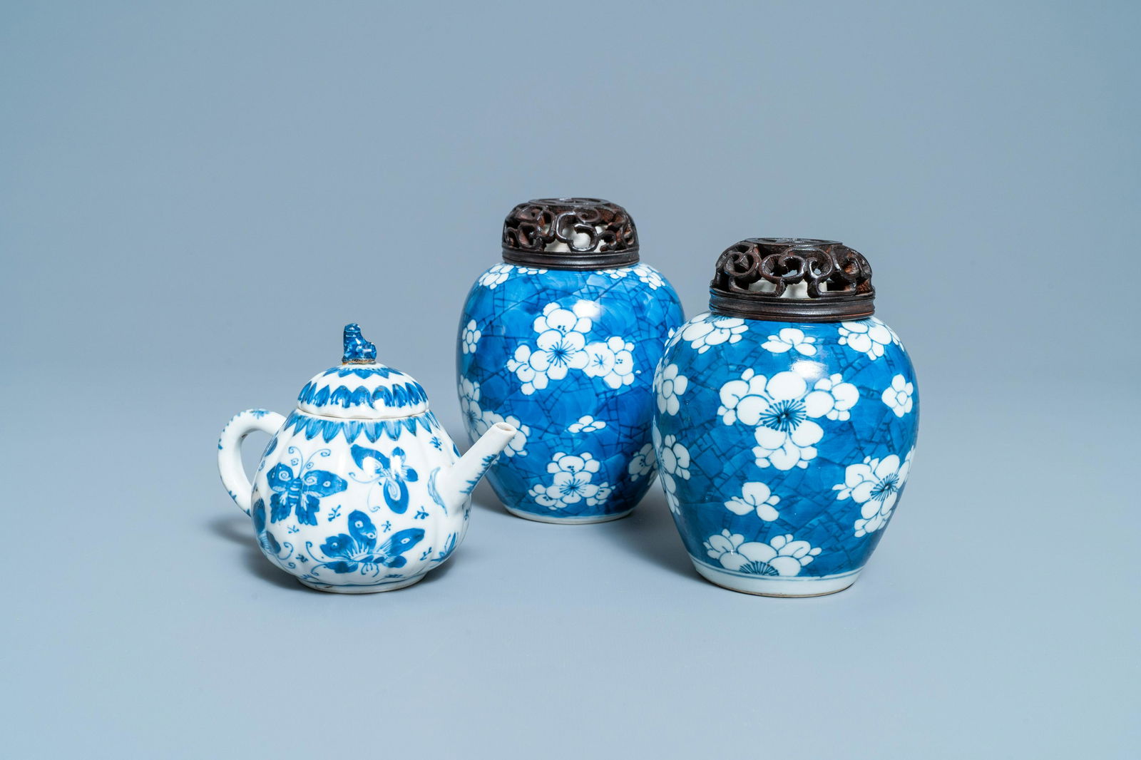 A pair of Chinese blue and white 'prunus on cracked: Full title: A pair of Chinese blue and white 'prunus on cracked ice' jars and a 'butterfly' teapot and cover, Kangxi Description: H.: 14,5 cm (the jars, excl. the lid) L.: 15 cm - H.: 11 cm (the teapo