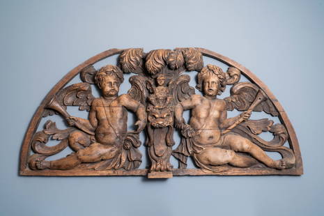 A reticulated carved oak fronton with two winged: Full title: A reticulated carved oak fronton with two winged cherubs holding a horn, France, 17th C. Description: L.: 137 cm - H.: 65 cm Provenance: - The Davioud-Larminet collection, Lille,