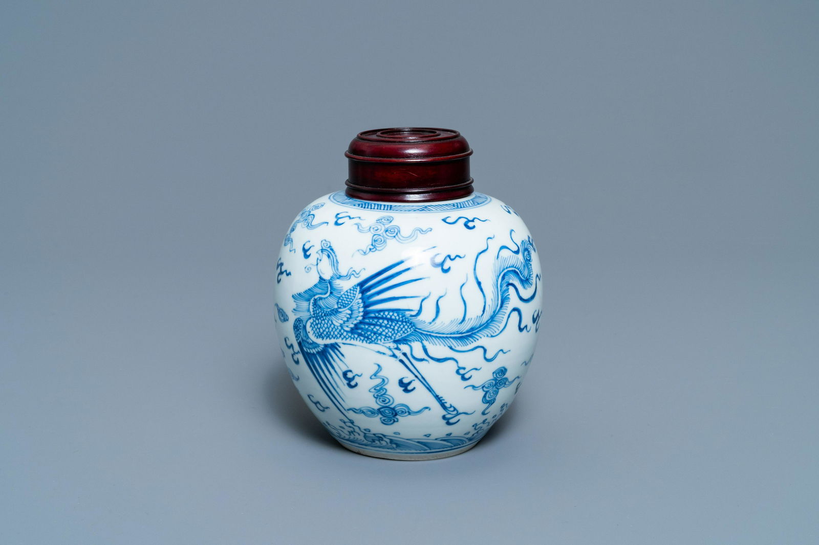 A Chinese blue and white 'dragon and phoenix' jar with: Full title: A Chinese blue and white 'dragon and phoenix' jar with wooden lid, Chenghua mark, Kangxi Description: H.: 17 cm (incl. the wooden cover) H.: 15 cm (the jar) The absence of a condition repo