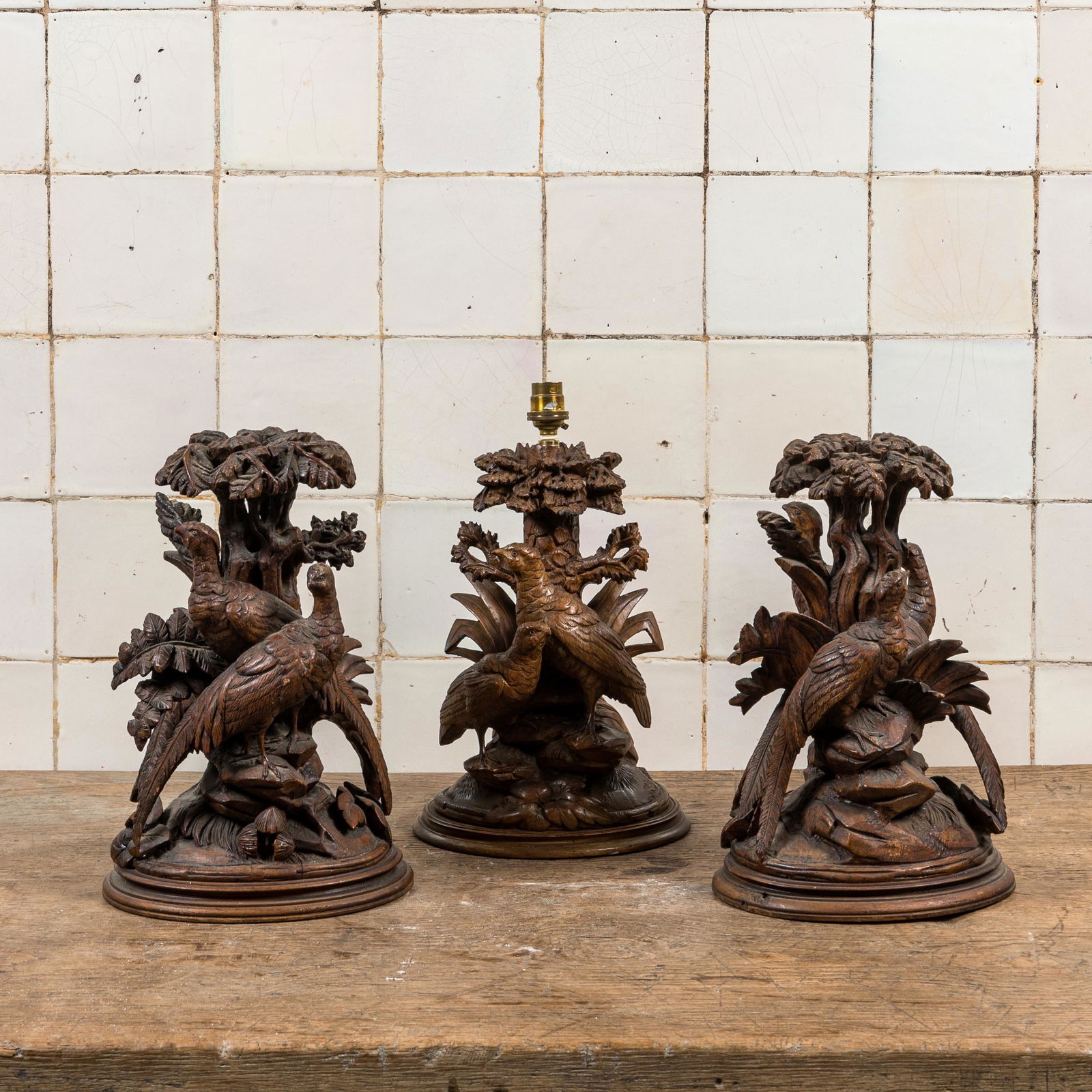 Three 'Black Forest' wooden sculptures depicting birds under foliage, one of which mounted as a (1 of 2)