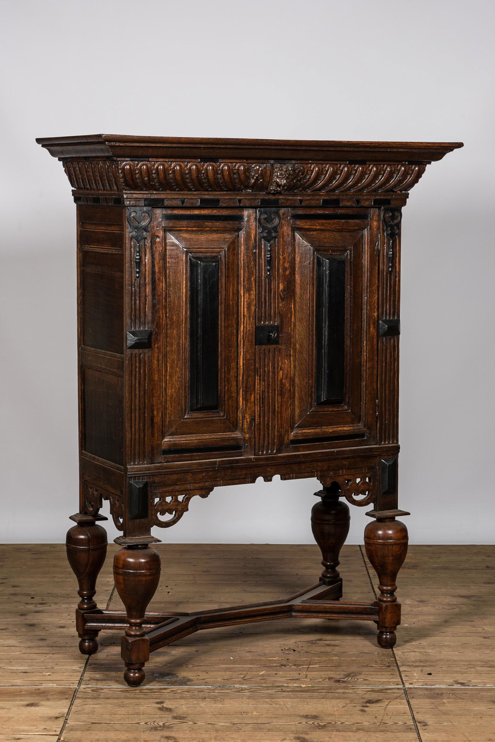 An oak and partly ebonised wooden two-door cupboard on foot, 19th C. (1 of 3)