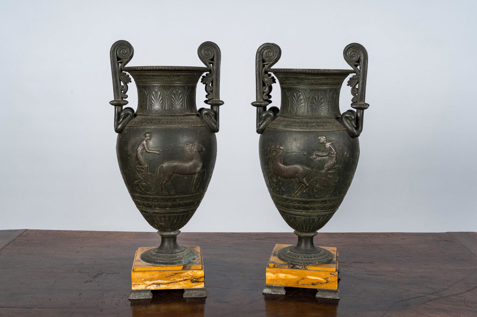 A pair of neoclassical style vases with charioteers on a Siena marble base, 19/20th C. (1 of 3)