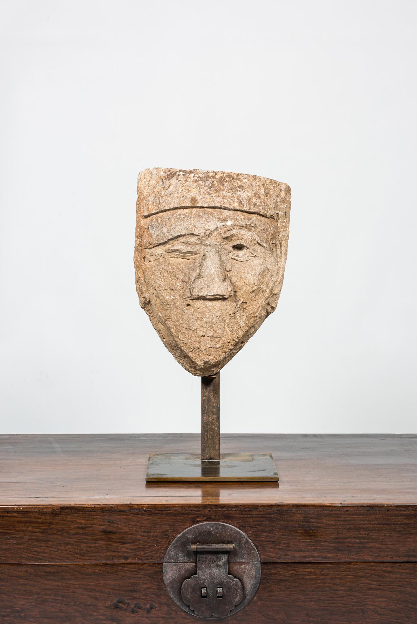 A large carved stone head of a winking man, 15th C. or later (1 of 3)