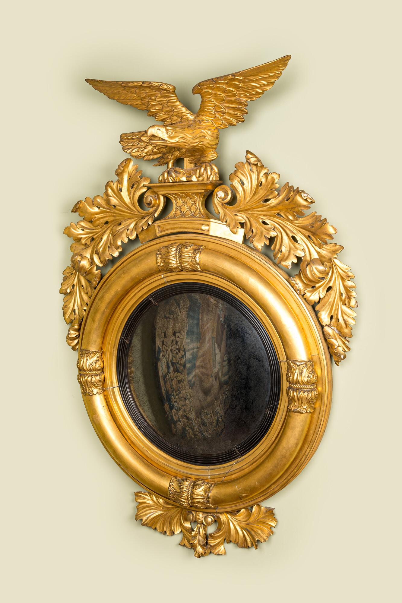 An impressive gilt wooden eagle-topped mirror with ebonised inner medallion, 19th C. (1 of 2)