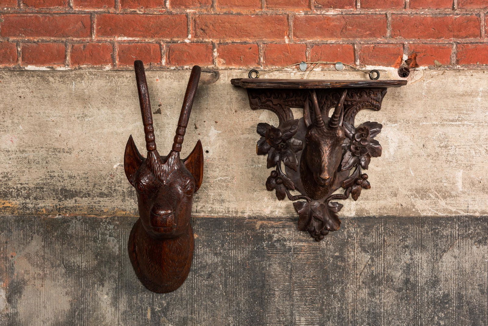 A carved wooden 'Black Forest' goat's head console and a carved oak head of a buck, Switzerland (1 of 2)