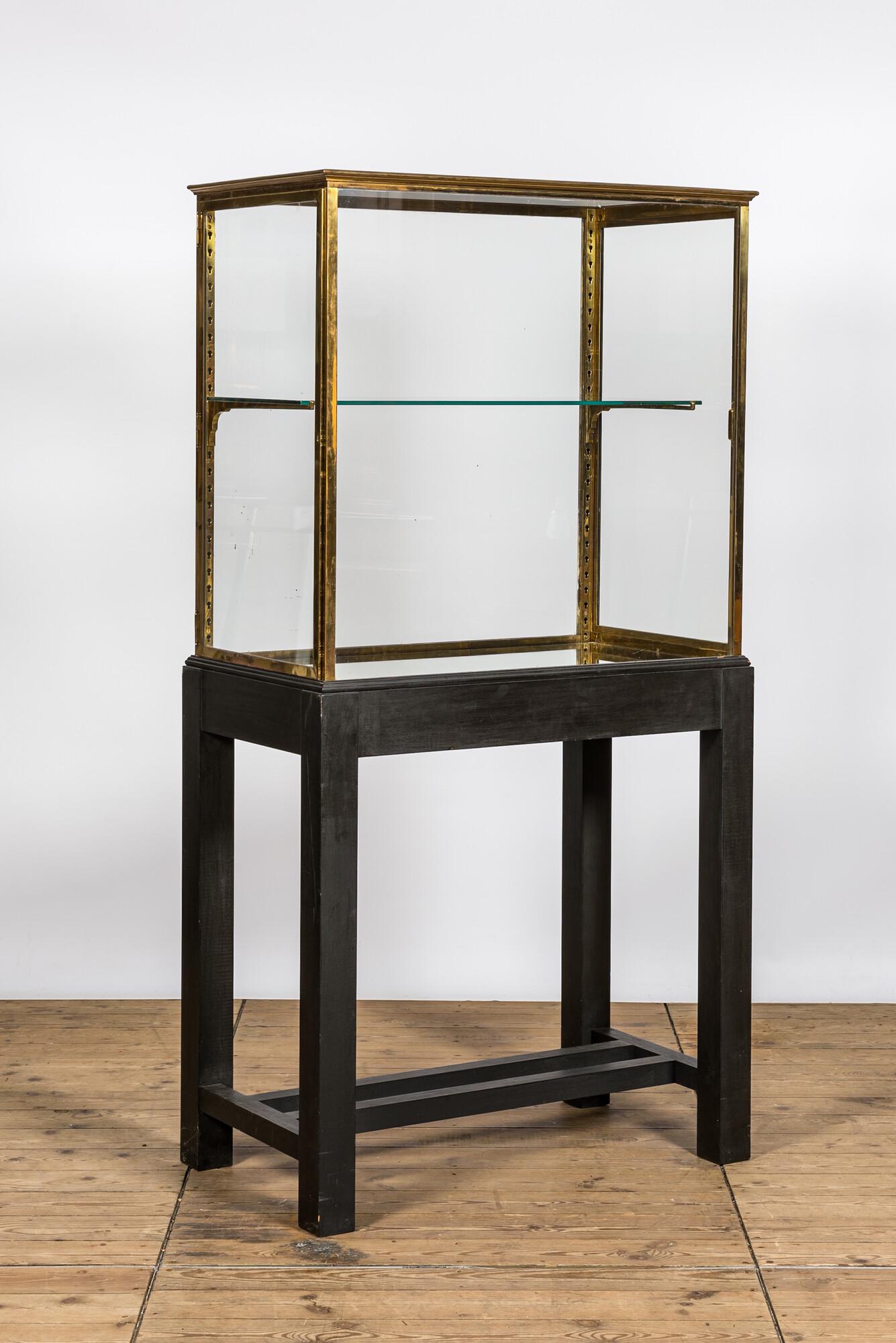 A French brass display cabinet on later wooden stand, 20th C.: Full title: A French brass display cabinet on later wooden stand, 20th C. Description: H 183,5 x L 92 x D 52 cm About this sale: Paul De Grande is one of the major dealers of antique furniture, fine s