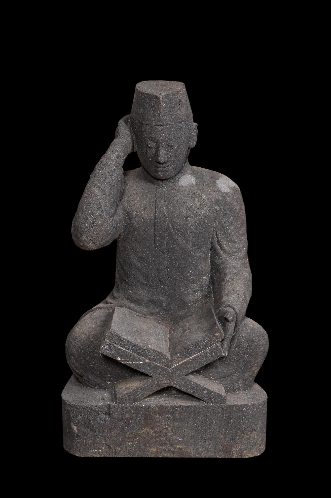 A basalt sculpture of a reading student, Indonesia, 20th C. (1 of 3)