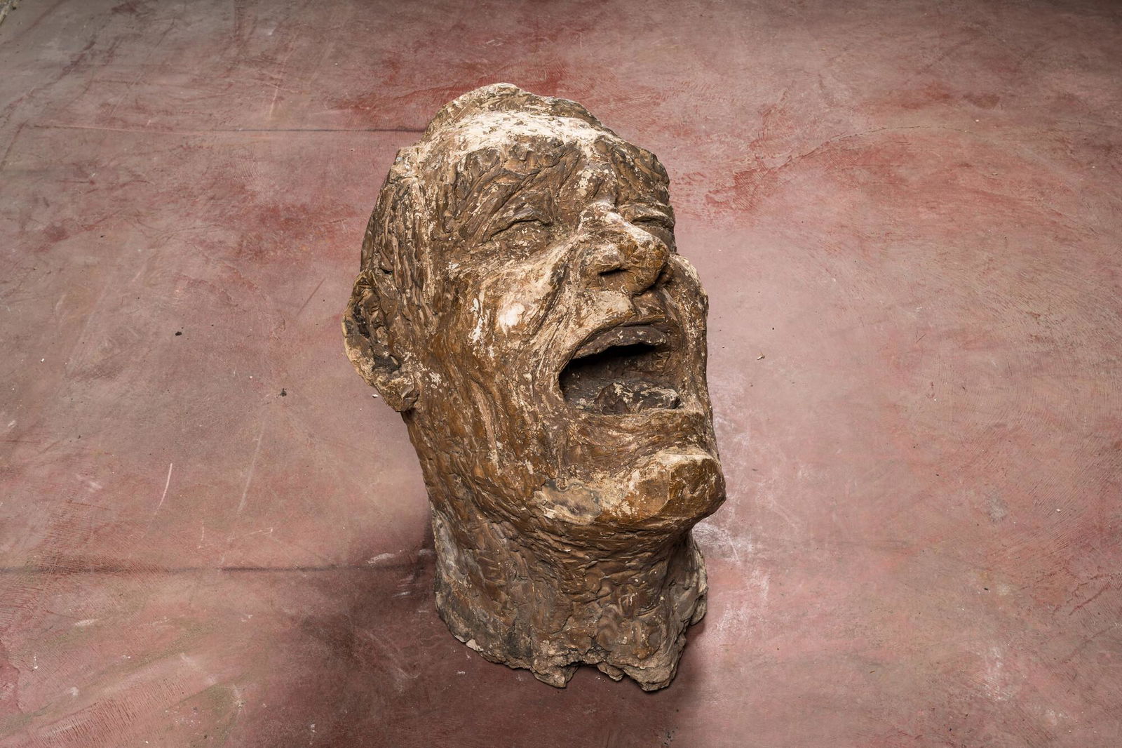 A large patinated terracotta head of a laughing man, 1st half 20th C. (1 of 3)