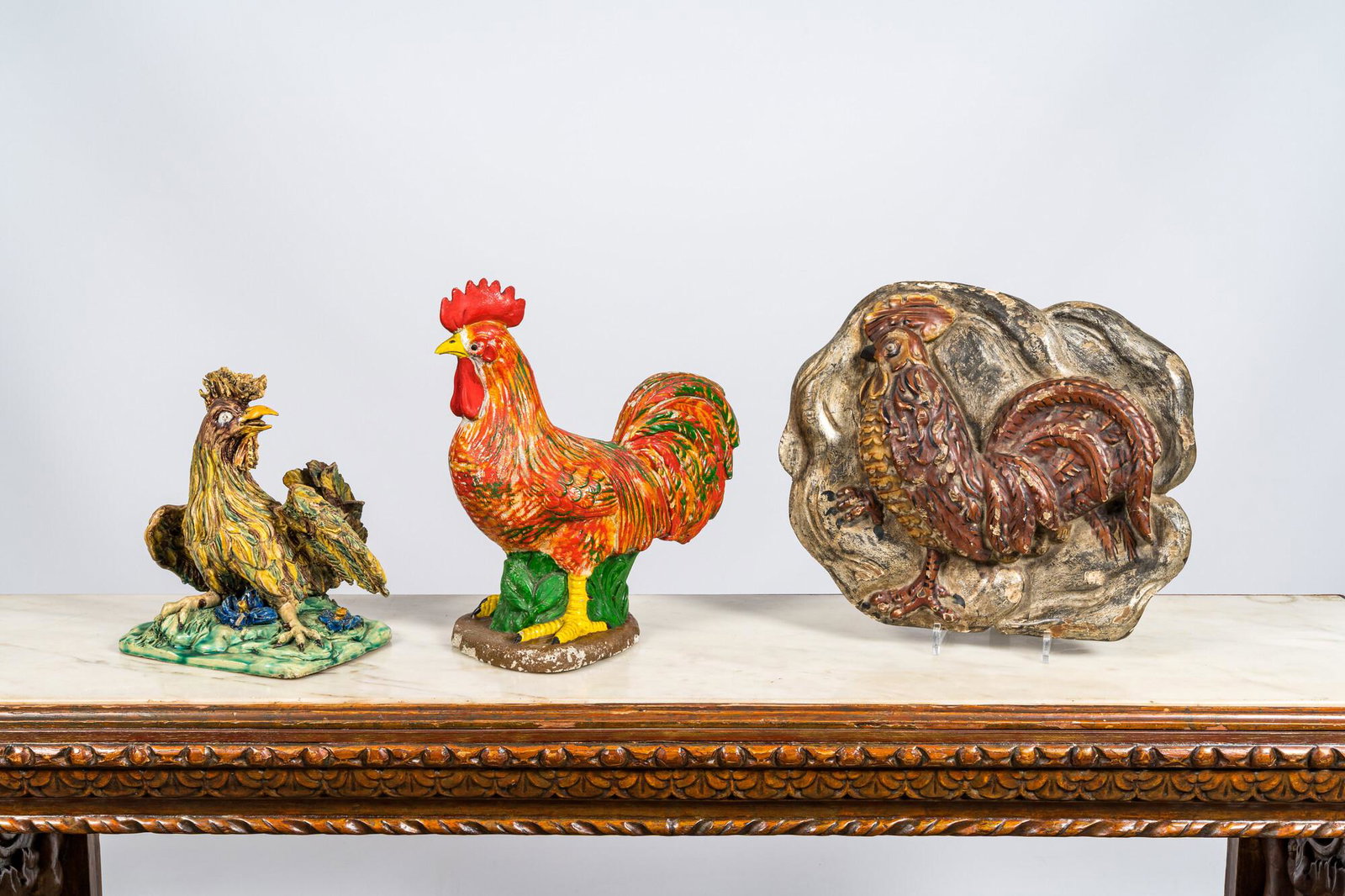 Two polychrome roosters in terracotta and composite stone and a wooden relief, 19/20th C. (1 of 2)