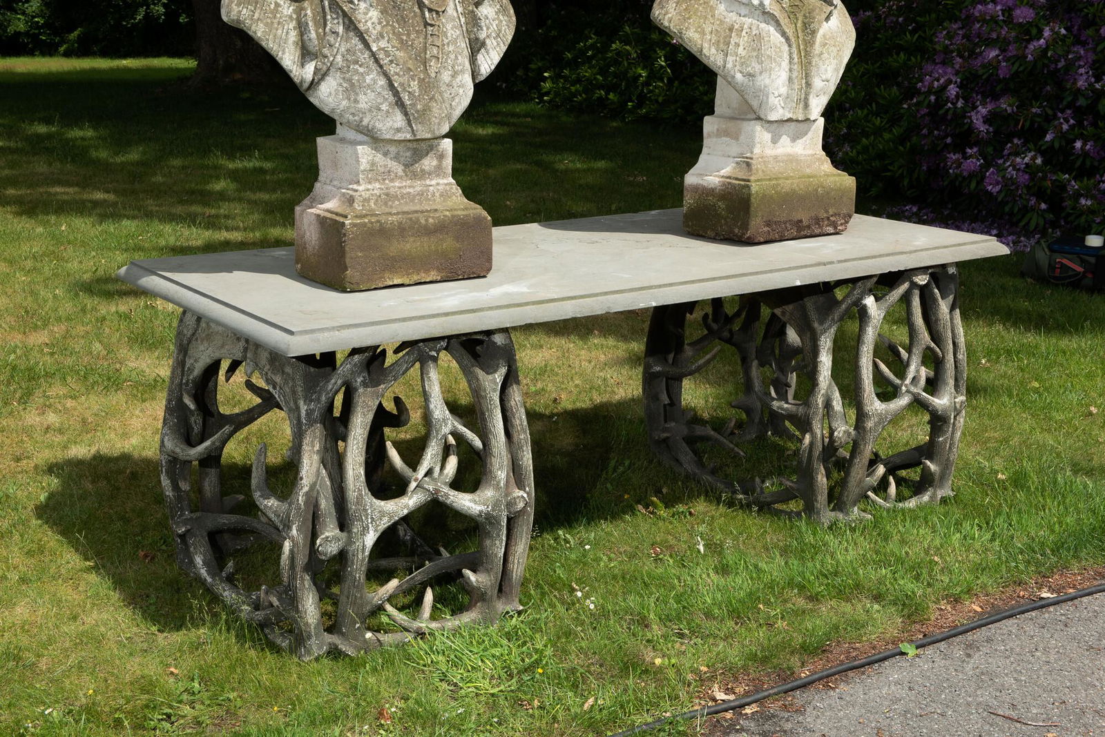 An impressive exterior table with bluestone top on entwined polyester antlers, 20th C. (1 of 4)