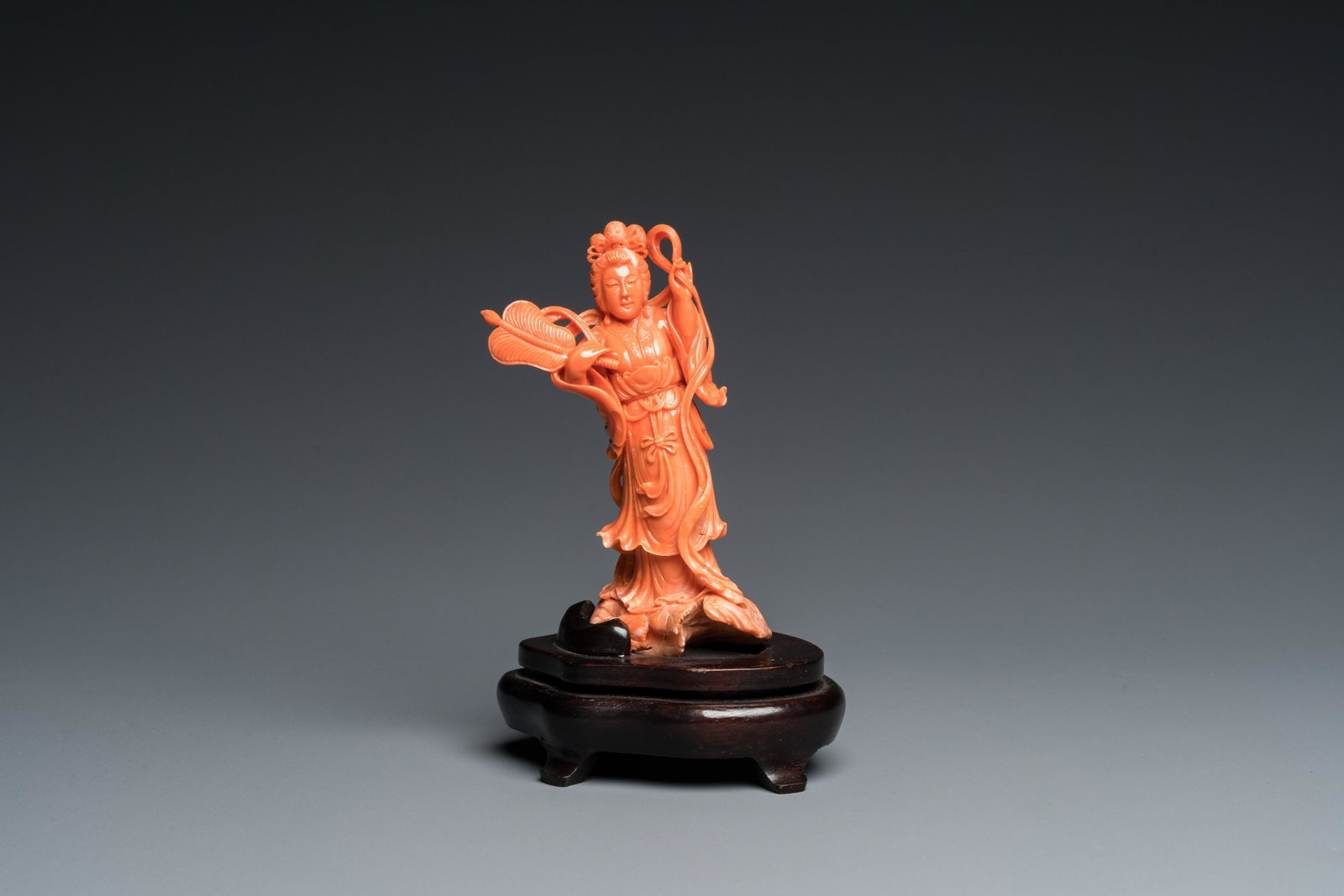 A Chinese red coral carving of Guanyin with a fan, 19/20th C.: H.: 16 cm (incl. stand) H.: 12,5 cm (the coral) Weight: 322 grams