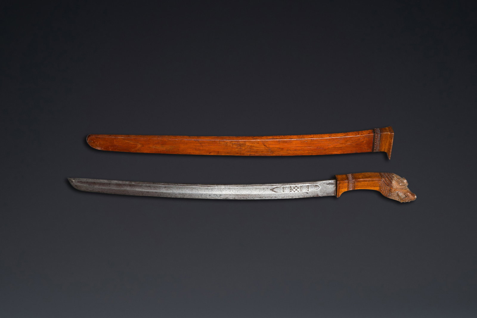 An Indonesian sword in wooden scabbard, dated 1891 and inscribed TJIPATJING: L.: 74,5 cm (the sword in scabbard) L.: 68 cm (the blade)