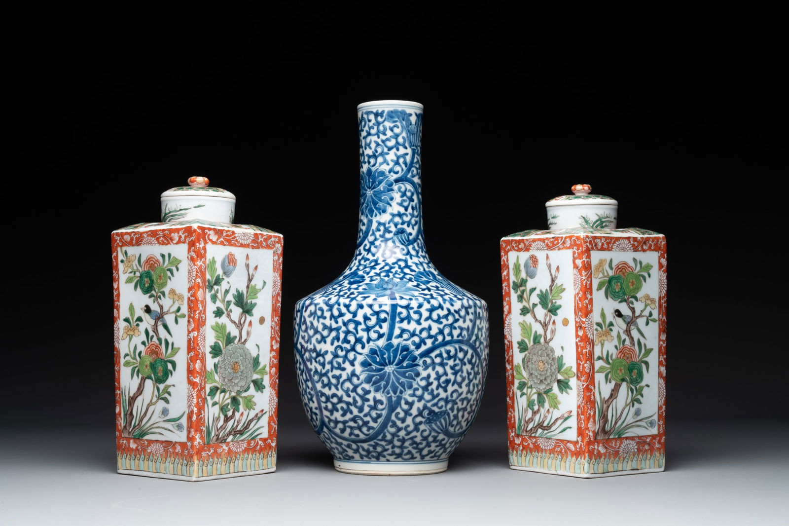 A Chinese blue and white bottle-shaped 'lotus scroll' vase and a pair of square famille verte flasks: A Chinese blue and white bottle-shaped 'lotus scroll' vase and a pair of square famille verte flasks and covers, 19th C. H.: 35,2 cm (the vase) H.: 28 cm (each flask, incl. cover)