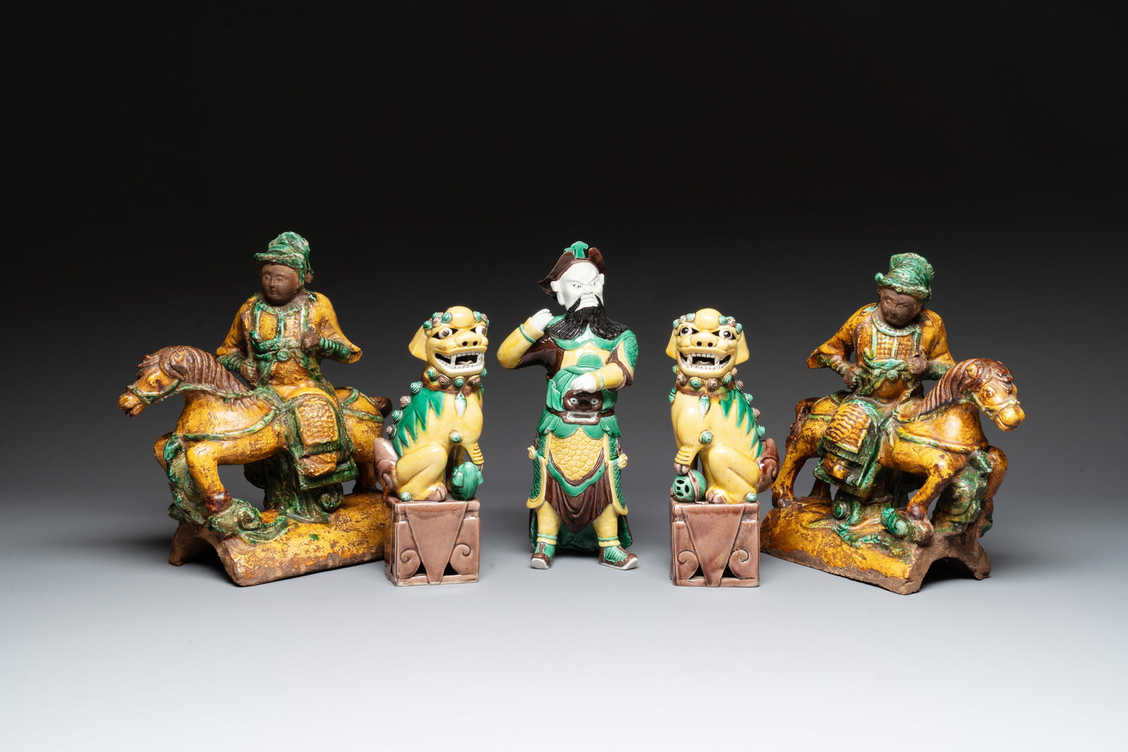 A pair of Chinese sancai-glazed rooftiles, a pair of Buddhist lions and a warrior, Ming and later: A pair of Chinese sancai-glazed rooftiles, a pair of Buddhist lions and a warrior, Ming and later H.: 32 cm (the warrior) H.: 31,5 cm (the warrior on horseback rooftiles) H.: 26 cm (the Buddhist lions
