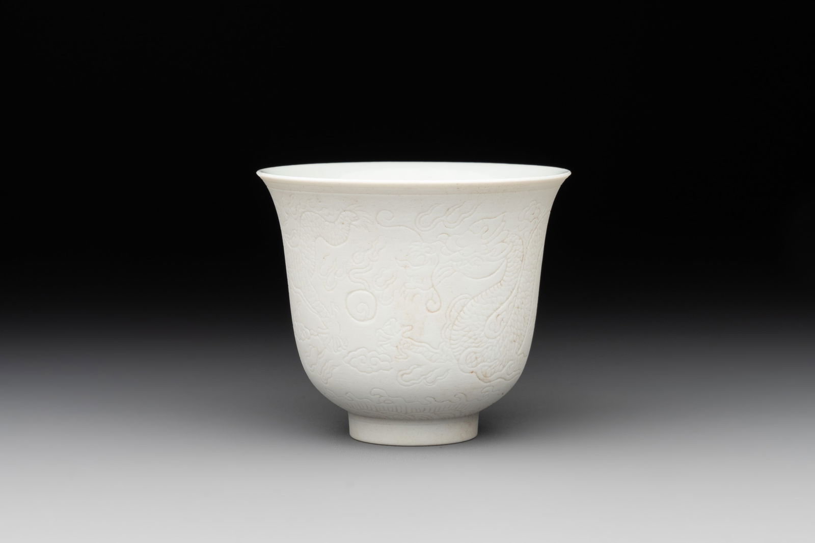 A Chinese white-glazed biscuit 'dragon' cup, Kangxi mark, 19th C. (1 of 7)