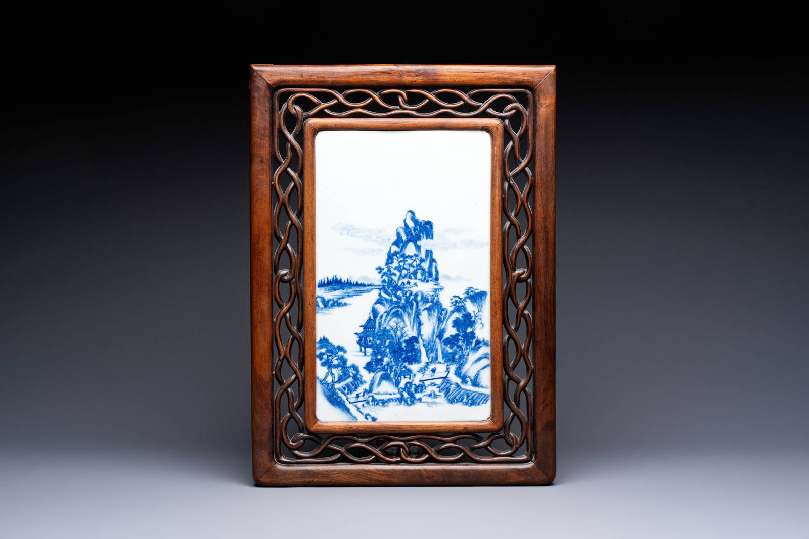 A Chinese blue and white 'mountainous landscape' plaque mounted in a wooden frame, 19/20th C.