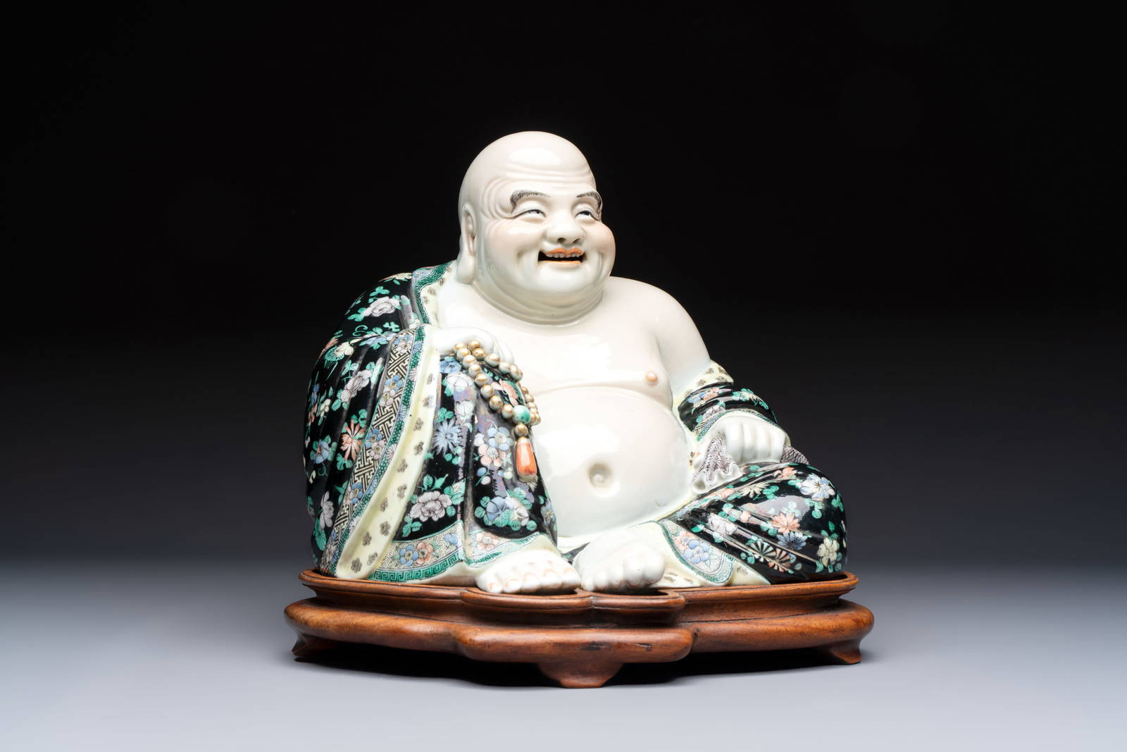 A Chinese famille verte black-ground Milefo Buddha on a wooden stand, Xue Chang Sen Zuo mark, 20th